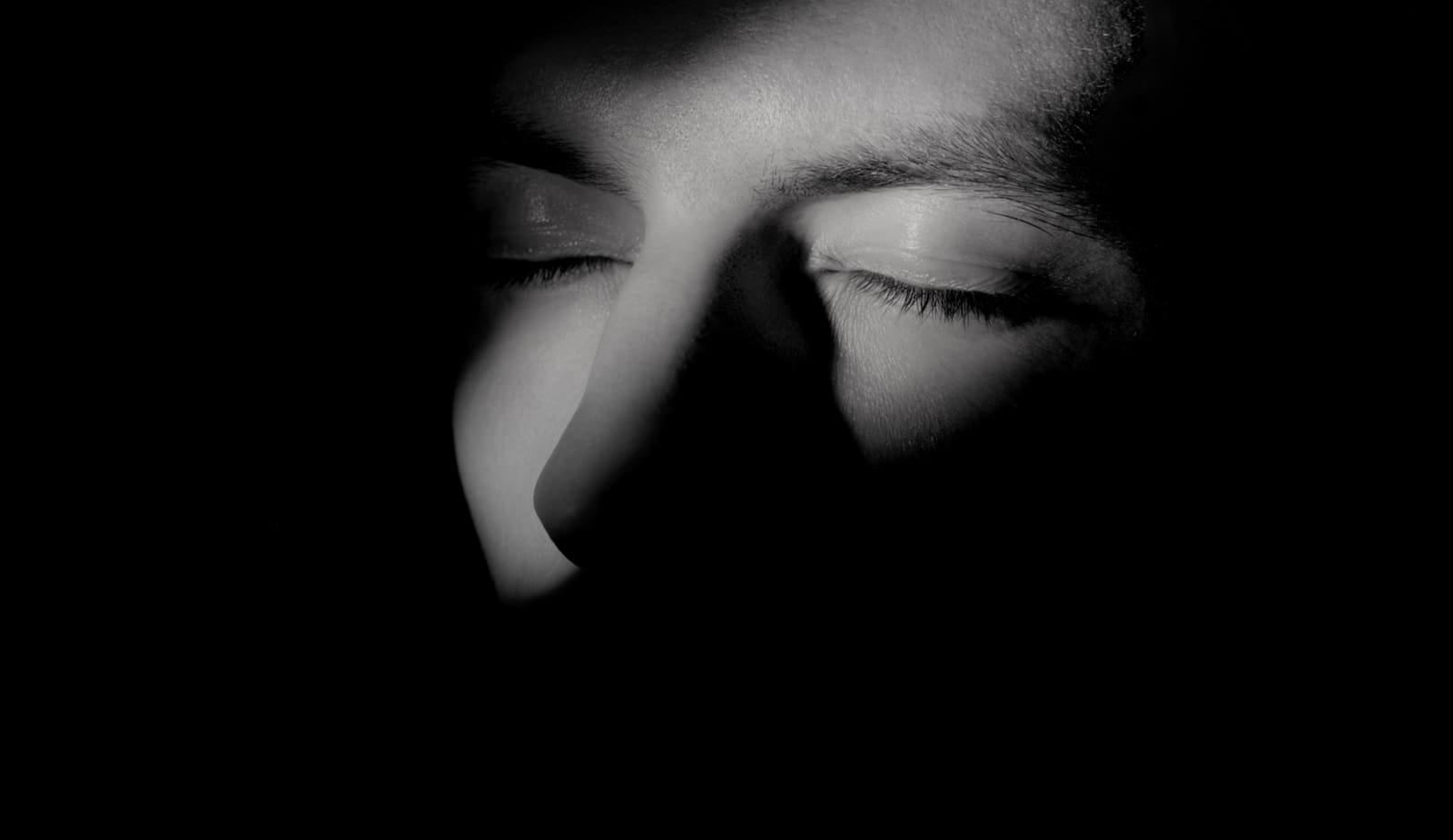 Un rostro con los ojos cerrados, en la oscuridad